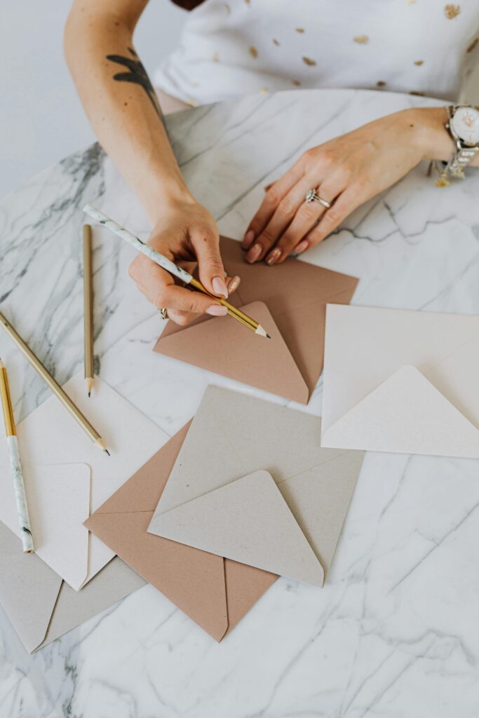 pexels-photo-4968667-4968667 Flat lay of hands writing on envelopes with pencils on marble surface.